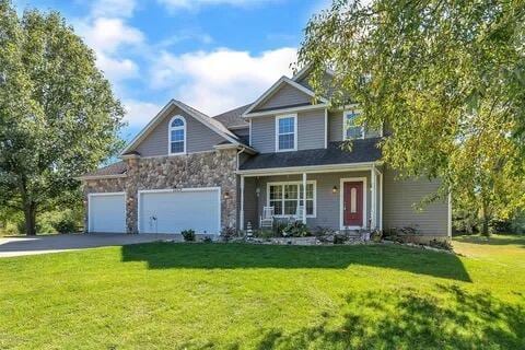 view of front of house featuring stone siding, driveway, a front yard, and a garage