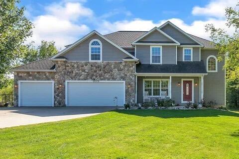 craftsman-style home featuring stone siding, an attached garage, concrete driveway, and a front yard