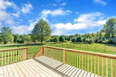 wooden terrace featuring a yard, a rural view, and fence