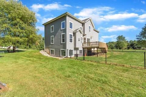 view of side of home featuring a lawn, a deck, and fence