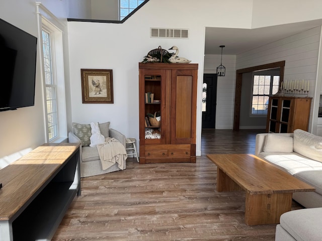 living area featuring wood finished floors, visible vents, and wood walls