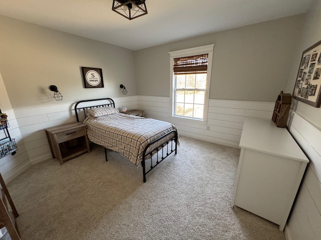 bedroom with carpet flooring, wood walls, and wainscoting