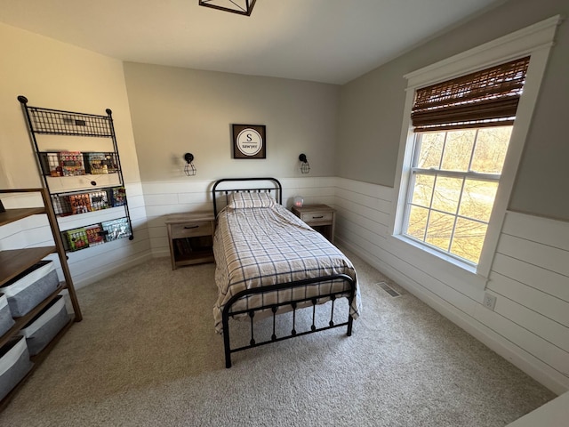 bedroom featuring a wainscoted wall, carpet floors, visible vents, and wood walls