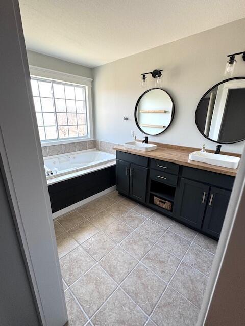 full bathroom with double vanity, tile patterned flooring, a bath, and a sink