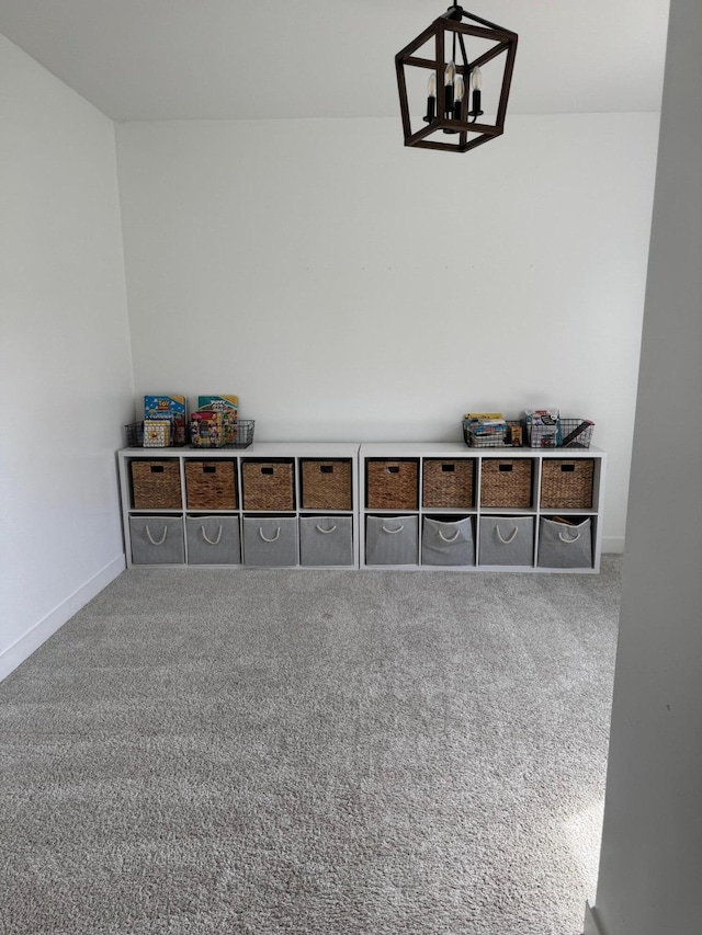 interior space featuring carpet flooring, baseboards, and a chandelier