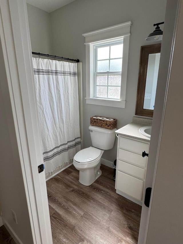 bathroom featuring curtained shower, baseboards, toilet, wood finished floors, and vanity