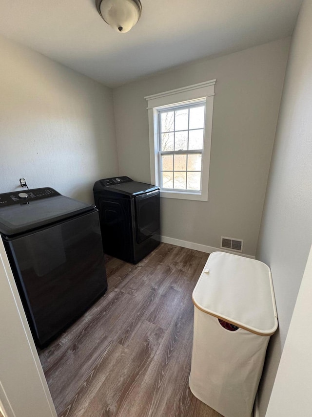 washroom with visible vents, wood finished floors, separate washer and dryer, baseboards, and laundry area