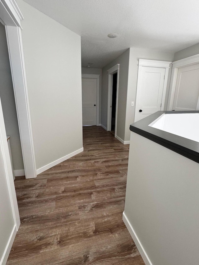 corridor with baseboards and dark wood-type flooring