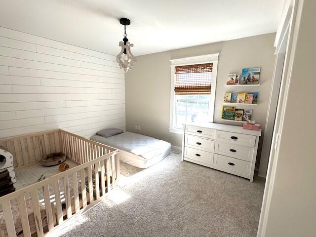 bedroom with wooden walls and light colored carpet