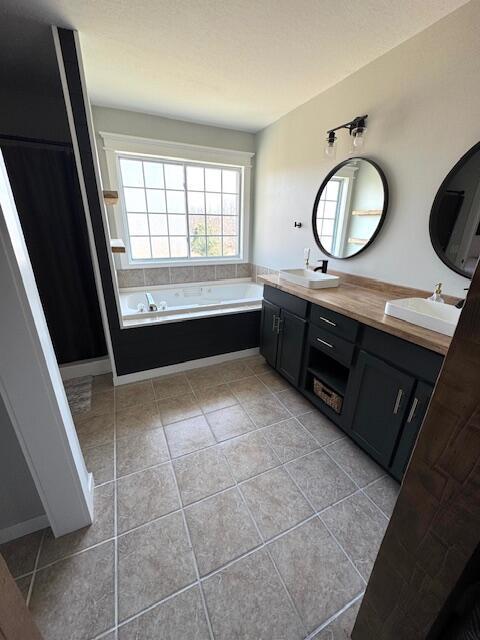 bathroom featuring tile patterned floors, double vanity, a garden tub, and a sink