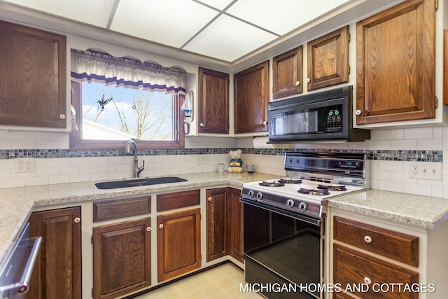 kitchen with tasteful backsplash, a sink, black microwave, range with gas stovetop, and stainless steel dishwasher