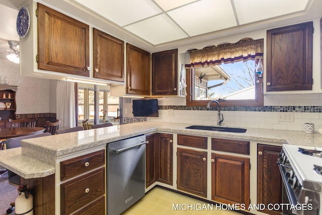 kitchen with plenty of natural light, a peninsula, stainless steel dishwasher, and a sink