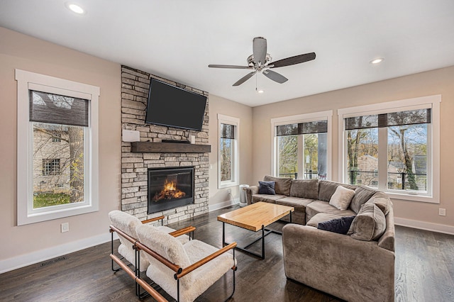 living area featuring visible vents, dark wood finished floors, recessed lighting, a stone fireplace, and baseboards