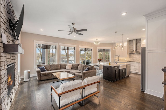 living room with a stone fireplace, recessed lighting, and dark wood finished floors