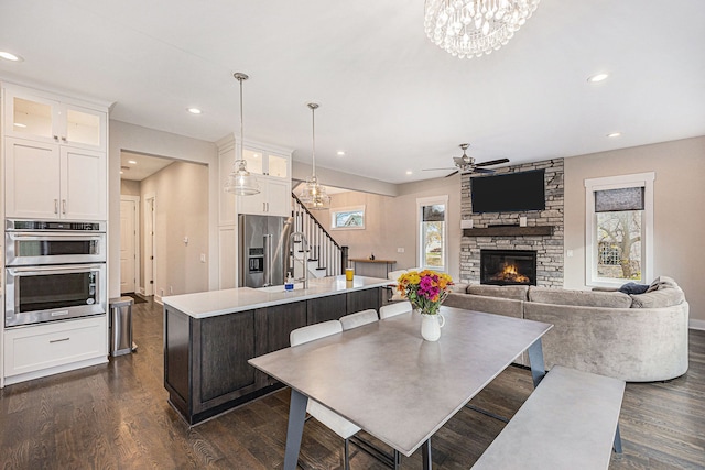 dining room featuring dark wood finished floors, stairway, plenty of natural light, and a fireplace