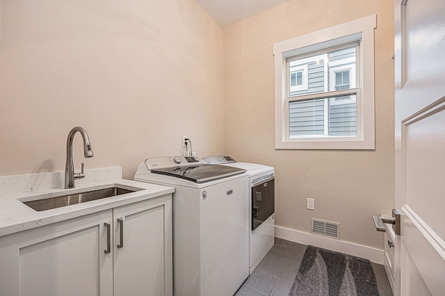 laundry room featuring baseboards, visible vents, cabinet space, separate washer and dryer, and a sink