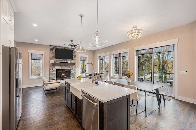 kitchen with a fireplace, dark wood-style flooring, a sink, stainless steel appliances, and open floor plan