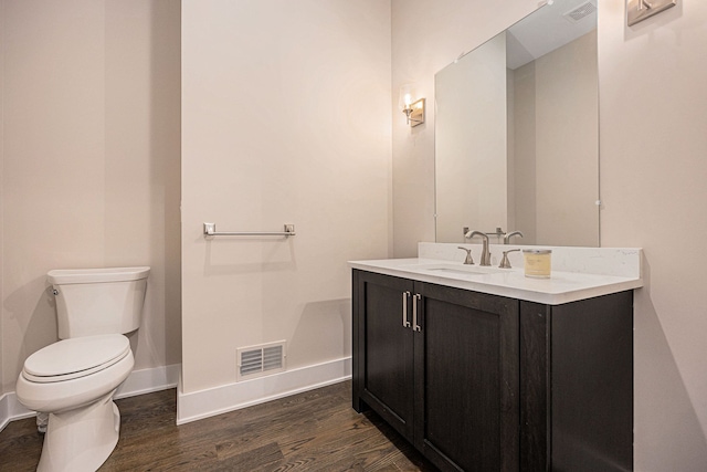 bathroom featuring vanity, wood finished floors, visible vents, baseboards, and toilet