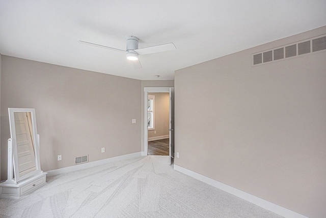 carpeted empty room featuring visible vents, a ceiling fan, and baseboards