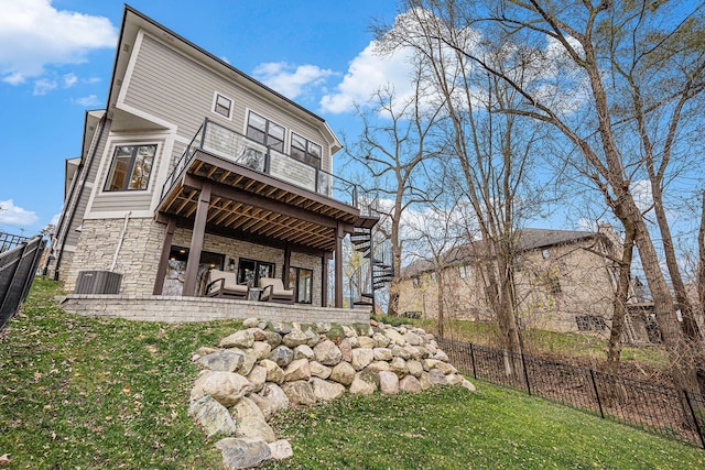 rear view of property with a wooden deck, a yard, stairs, stone siding, and fence private yard