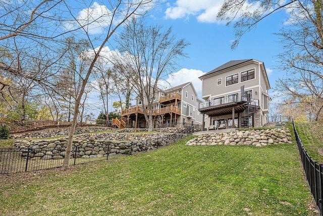 rear view of house with stairway, a lawn, a deck, and fence