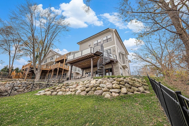 rear view of property featuring a lawn, stone siding, fence, stairway, and a wooden deck