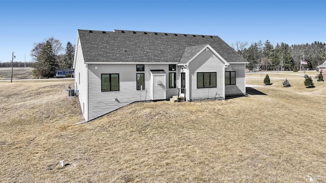 view of front of house with roof with shingles and a front yard