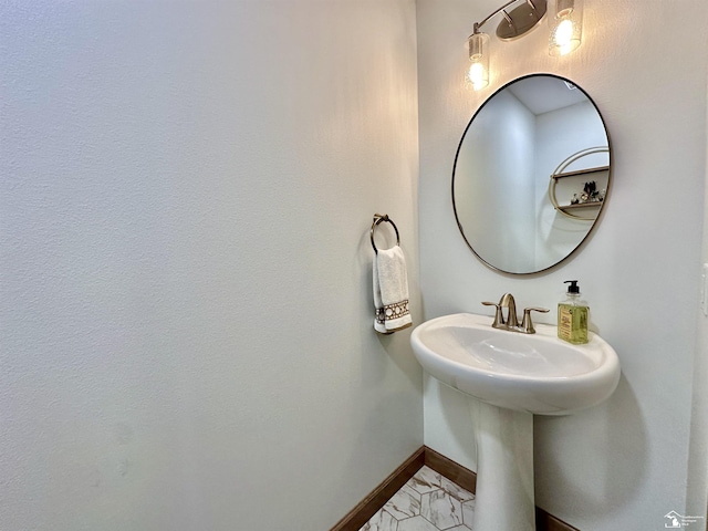 bathroom featuring marble finish floor, baseboards, and a sink