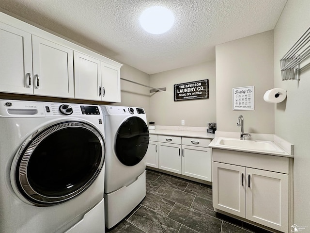 washroom featuring washer and dryer, cabinet space, a textured ceiling, and a sink