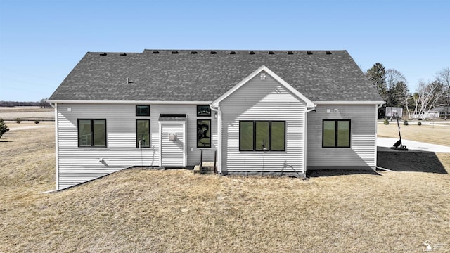 rear view of property featuring a yard and roof with shingles