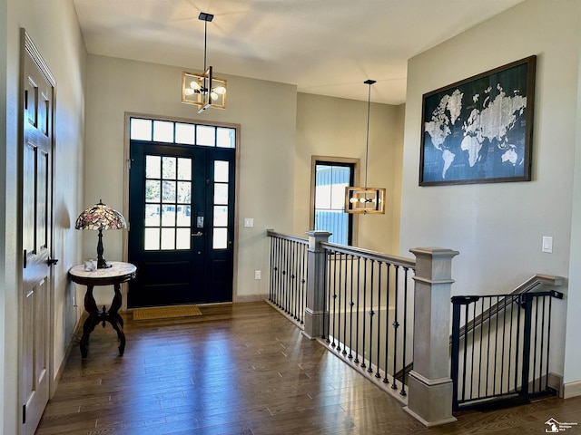 foyer featuring baseboards, an inviting chandelier, and hardwood / wood-style flooring