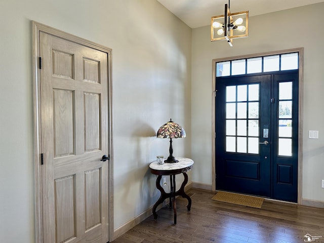 entrance foyer featuring an inviting chandelier, wood finished floors, and baseboards