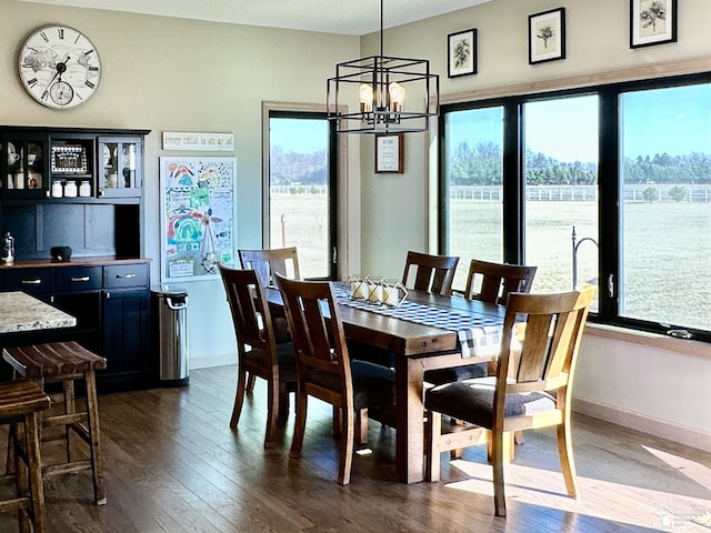 dining space with baseboards, a notable chandelier, and dark wood-style flooring