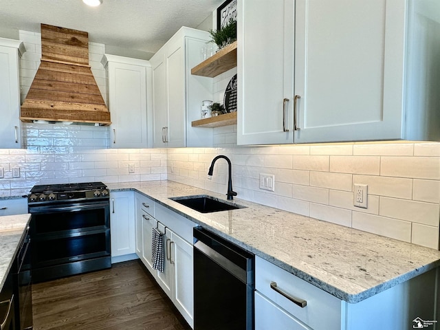 kitchen with dishwashing machine, double oven range, custom exhaust hood, open shelves, and a sink