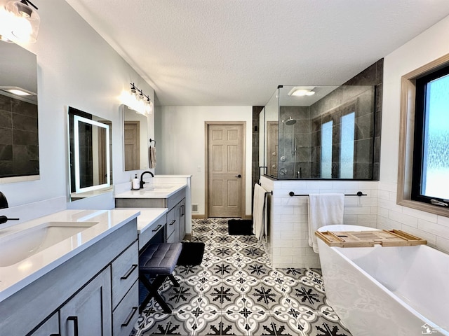 bathroom with a textured ceiling, two vanities, a walk in shower, and a sink