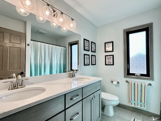 full bathroom with tile patterned floors, toilet, double vanity, and a sink