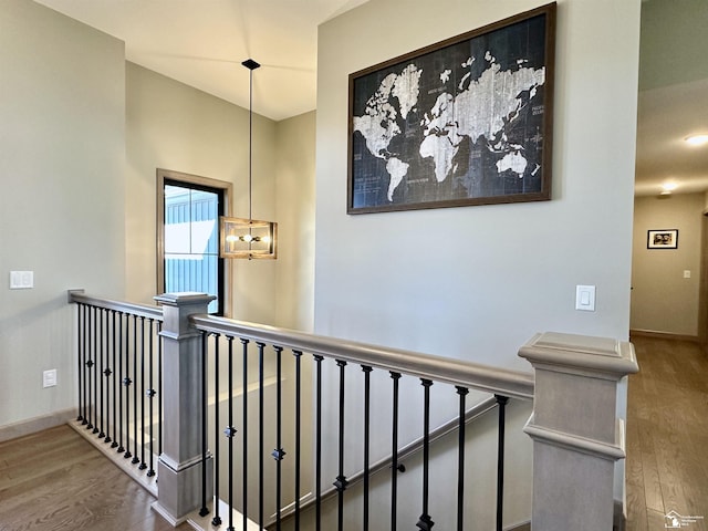 corridor featuring an upstairs landing, a notable chandelier, baseboards, and wood finished floors