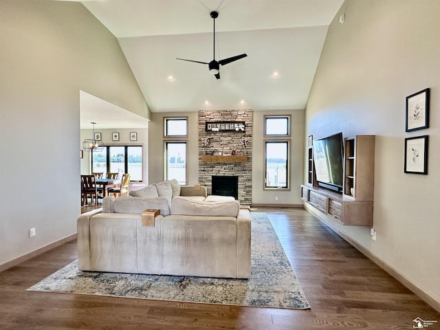 living area featuring baseboards, high vaulted ceiling, wood finished floors, and a fireplace