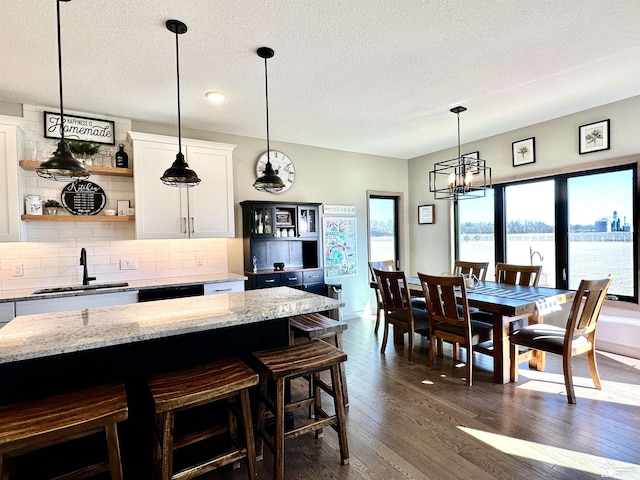 kitchen featuring a sink, backsplash, dark wood-style floors, white cabinets, and open shelves