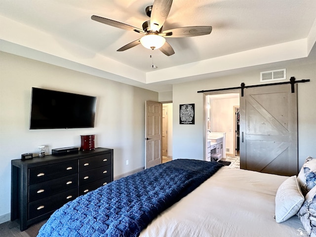 bedroom with visible vents, a ceiling fan, baseboards, a barn door, and a raised ceiling