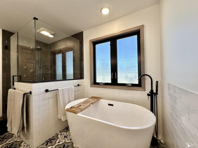 full bath featuring a wainscoted wall, a freestanding bath, a shower stall, tile walls, and tile patterned floors