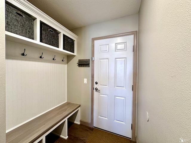 mudroom with dark wood finished floors and a textured wall