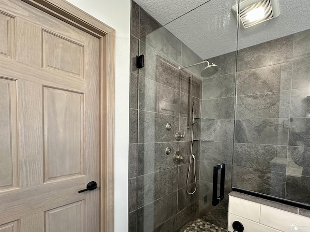 full bathroom with visible vents, a stall shower, and a textured ceiling