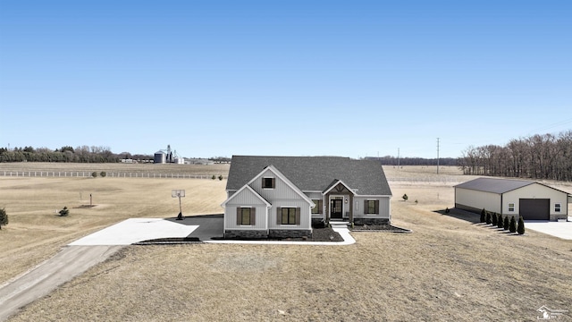 view of front of home with board and batten siding, a shingled roof, a garage, an outbuilding, and driveway