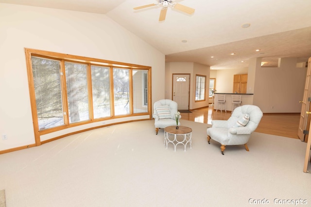 living area featuring lofted ceiling, light colored carpet, baseboards, and ceiling fan