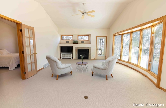 living area featuring visible vents, baseboards, lofted ceiling, carpet floors, and a tile fireplace