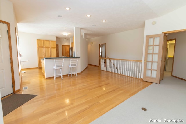 interior space with dark countertops, a breakfast bar area, light wood-style flooring, and freestanding refrigerator