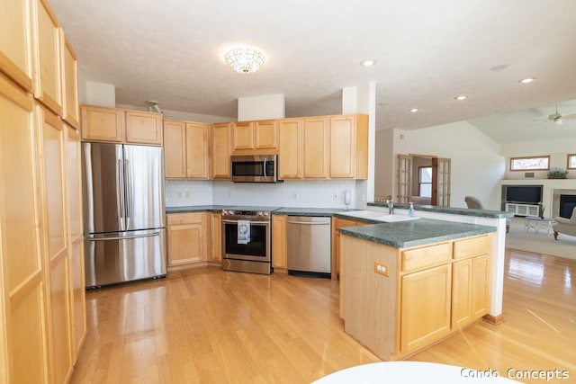 kitchen featuring a peninsula, light brown cabinets, appliances with stainless steel finishes, and a sink