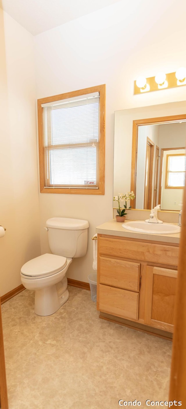 bathroom featuring toilet, vanity, and baseboards