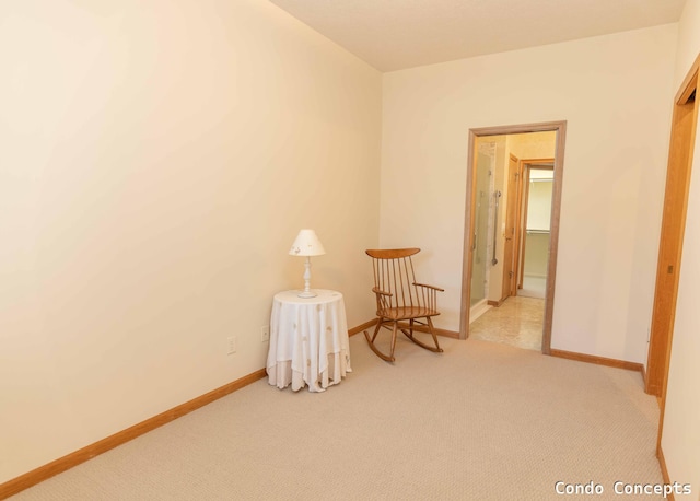 sitting room with baseboards and light carpet